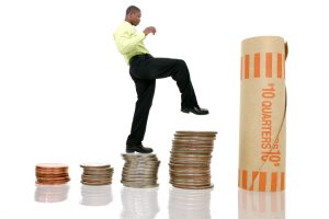 Young man in business attire climbinb giant stacks of money. Shot in studio over white.